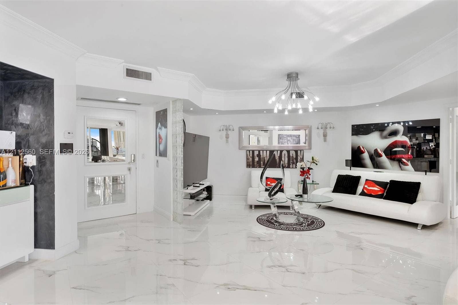 4000 Island Boulevard, #701, Aventura, FL 33160 Open living space featuring high-gloss large-format flooring, custom multi-arm chandelier, decorative glass block wall accent, and recessed ceiling lighting