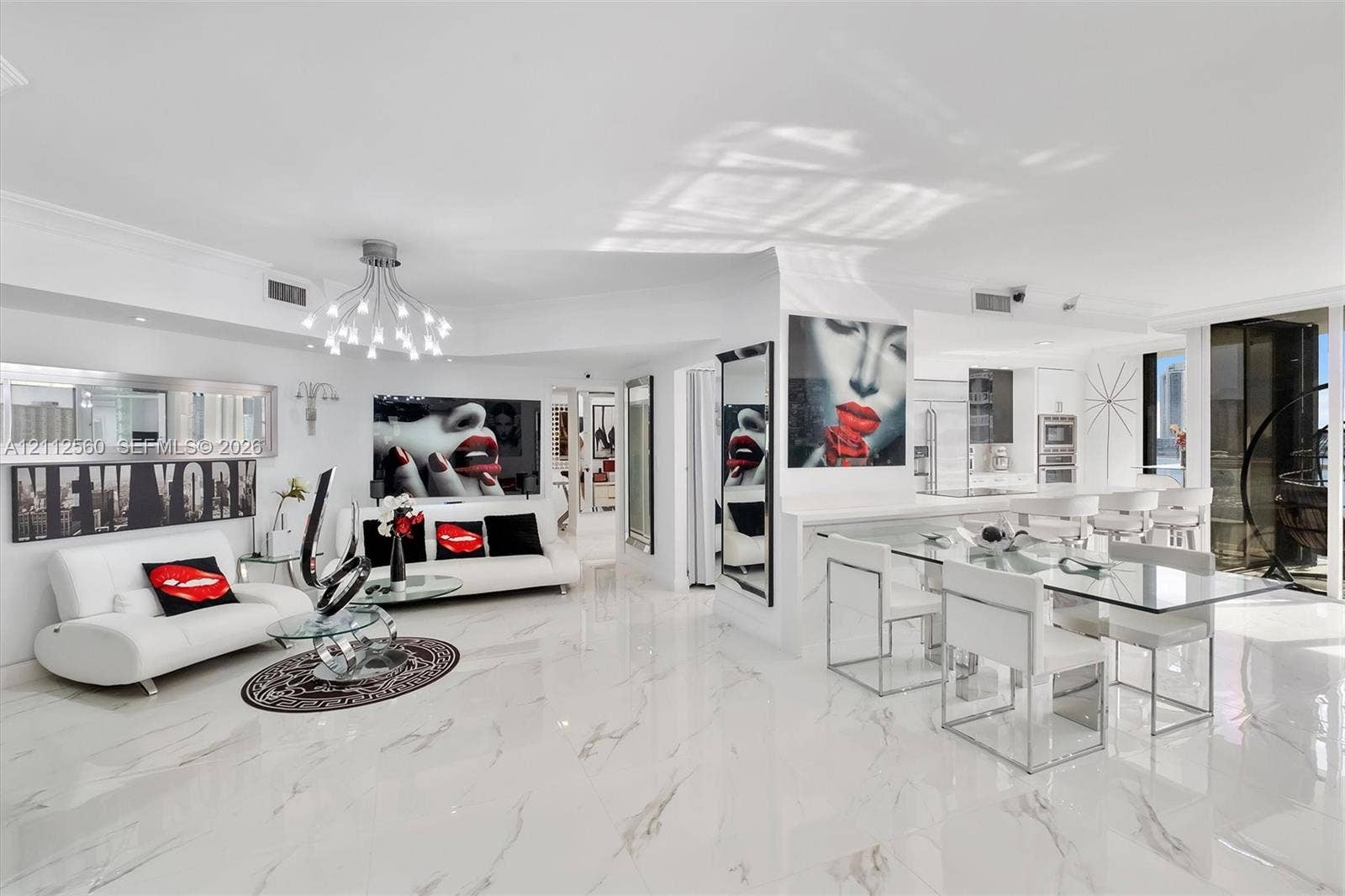 4000 Island Boulevard, #701, Aventura, FL 33160 Open-concept living space featuring high-gloss large-format tile flooring, multi-arm chandelier lighting, sleek built-in cabinetry, and integrated kitchen appliances
