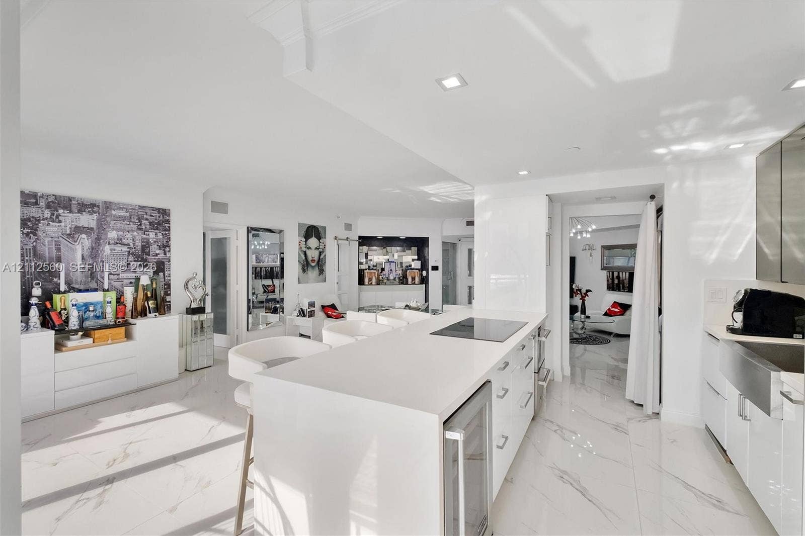 4000 Island Boulevard, #701, Aventura, FL 33160 Kitchen featuring a central island with a solid-surface countertop, an integrated electric cooktop, and an under-counter wine refrigerator, complemented by stone-finish flooring and a stainless steel farmhouse-style sink