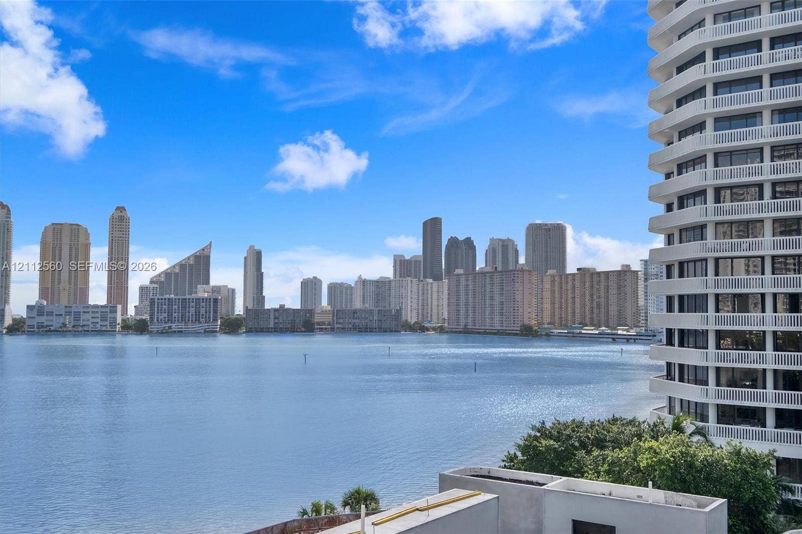 4000 Island Boulevard, #701, Aventura, FL 33160 Expansive balcony featuring white railings, overlooking a large body of water and a metropolitan skyline