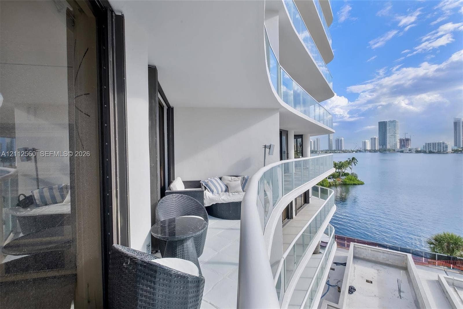 4000 Island Boulevard, #701, Aventura, FL 33160 Curved wrap-around balcony featuring glass panel railings, white flooring, and wide-reaching water frontage