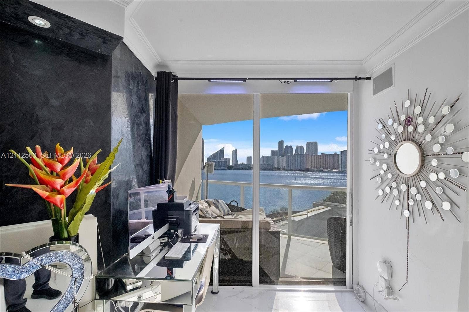 4000 Island Boulevard, #701, Aventura, FL 33160 Floor-to-ceiling glass sliding doors opening to a balcony with water and skyline scenery, featuring a textured black feature wall, recessed lighting, and crown molding
