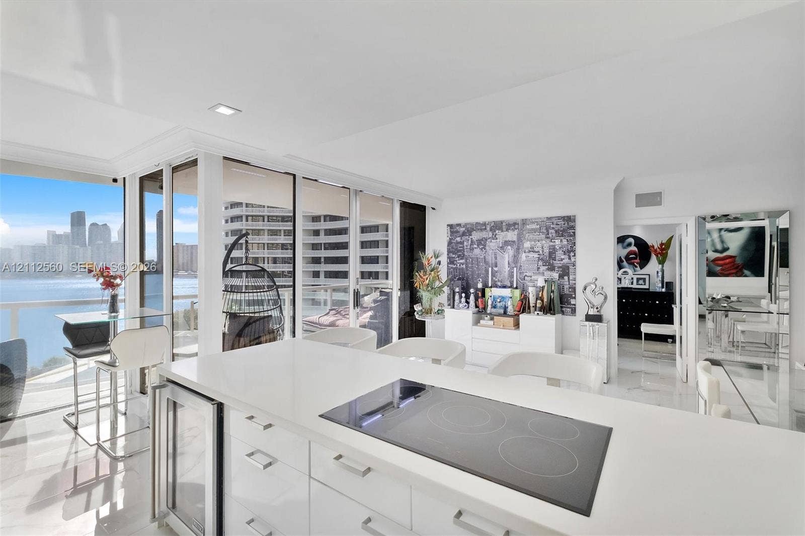 4000 Island Boulevard, #701, Aventura, FL 33160 Open-concept kitchen featuring an island with a quartz countertop, an integrated glass cooktop, a built-in under-counter beverage refrigerator, and floor-to-ceiling glass panel walls