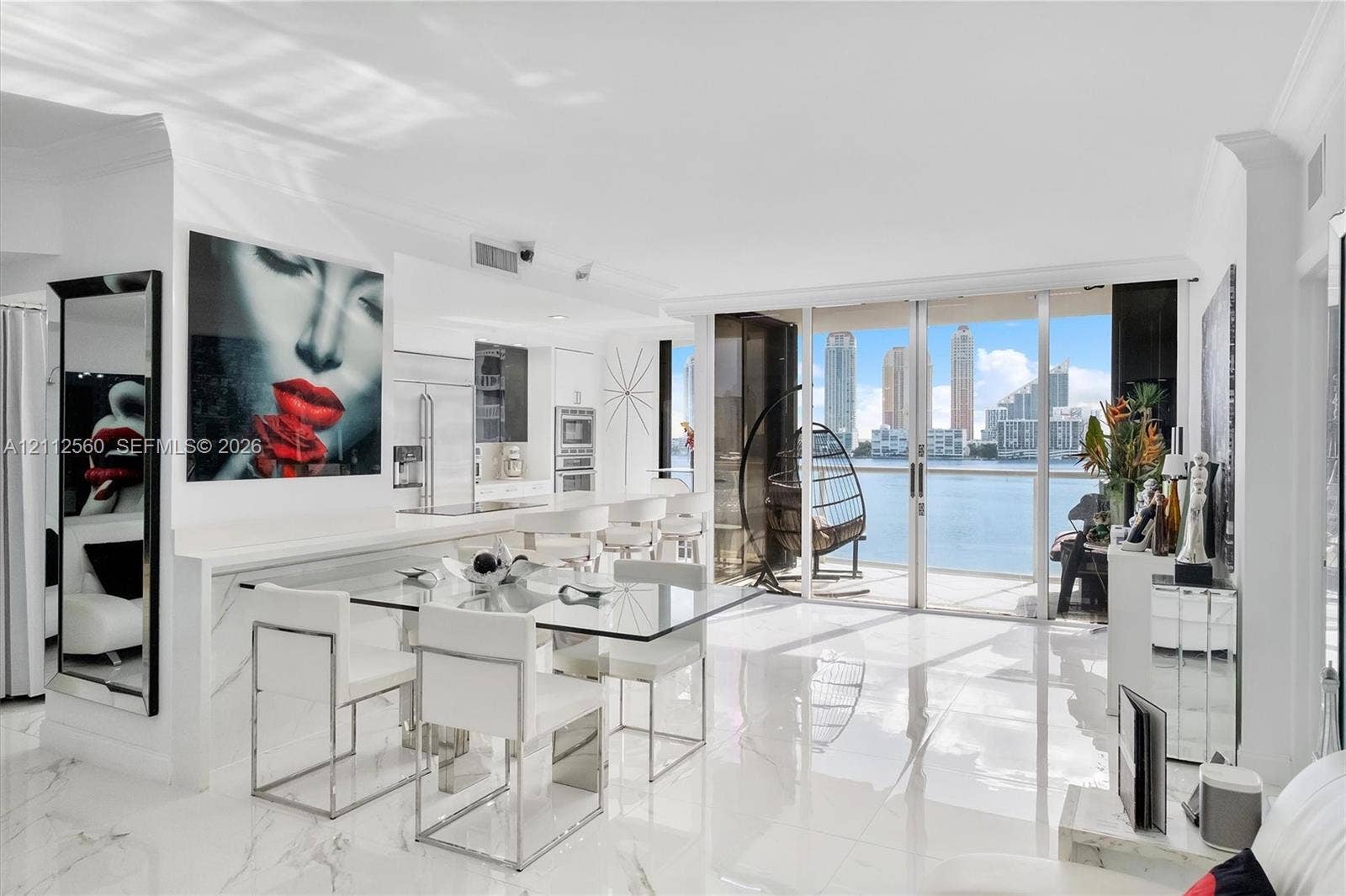 4000 Island Boulevard, #701, Aventura, FL 33160 Open-concept living space featuring high-gloss stone-finish flooring, floor-to-ceiling glass sliding doors, and white cabinetry