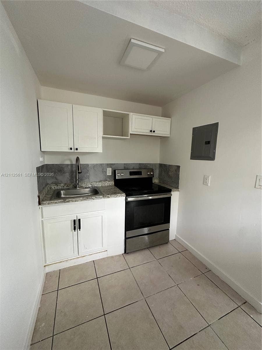 6901 NW 8th Avenue, #2, Miami, Miami, FL 33150 Kitchen featuring white cabinetry, stone-finish countertops, grey tile backsplash, stainless steel range, and tile flooring
