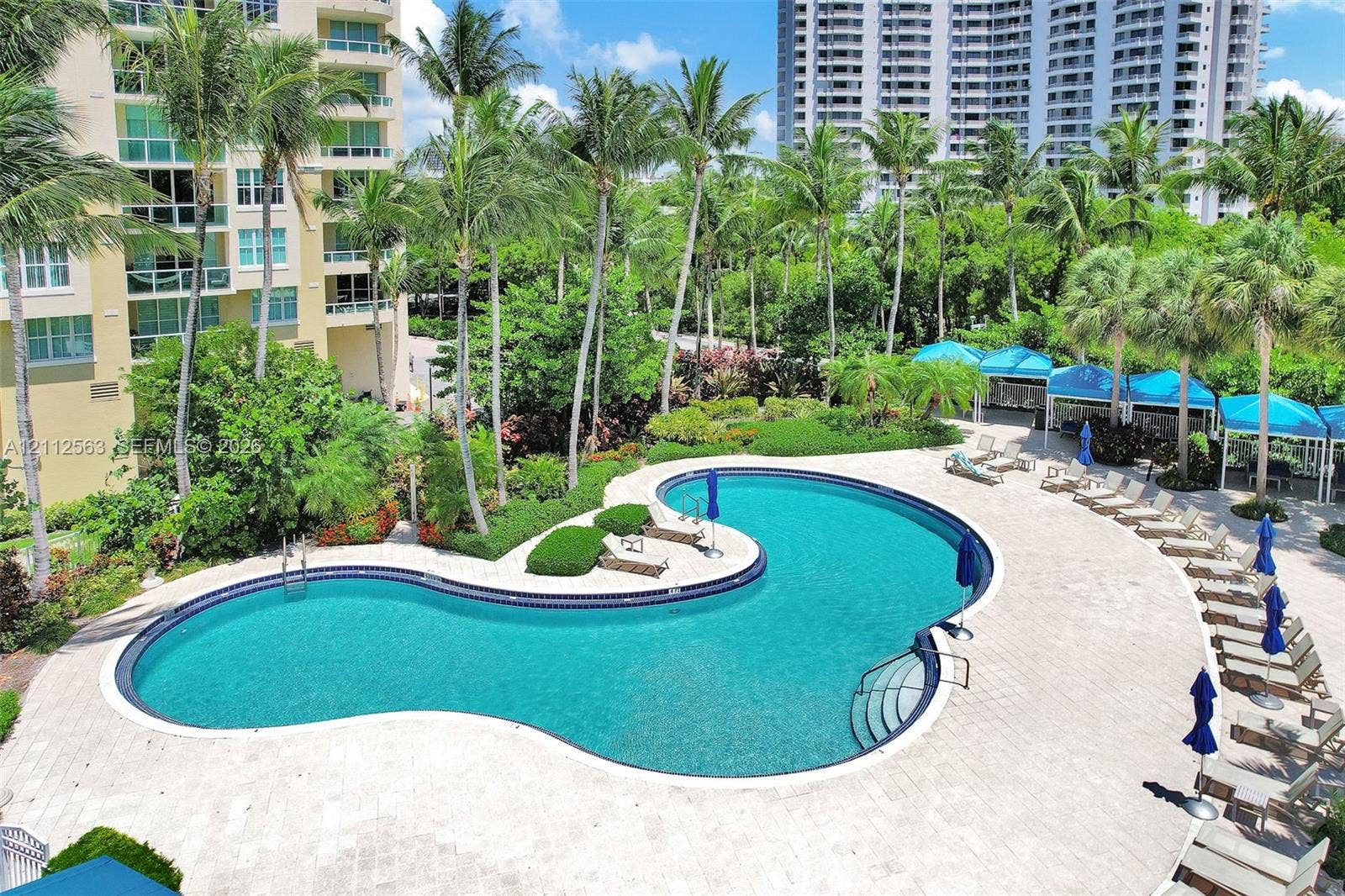 3330 NE 190th Street, #2016, Aventura, FL 33180 Freeform swimming pool with a stone paver deck, integrated landscaping, and mature palm trees