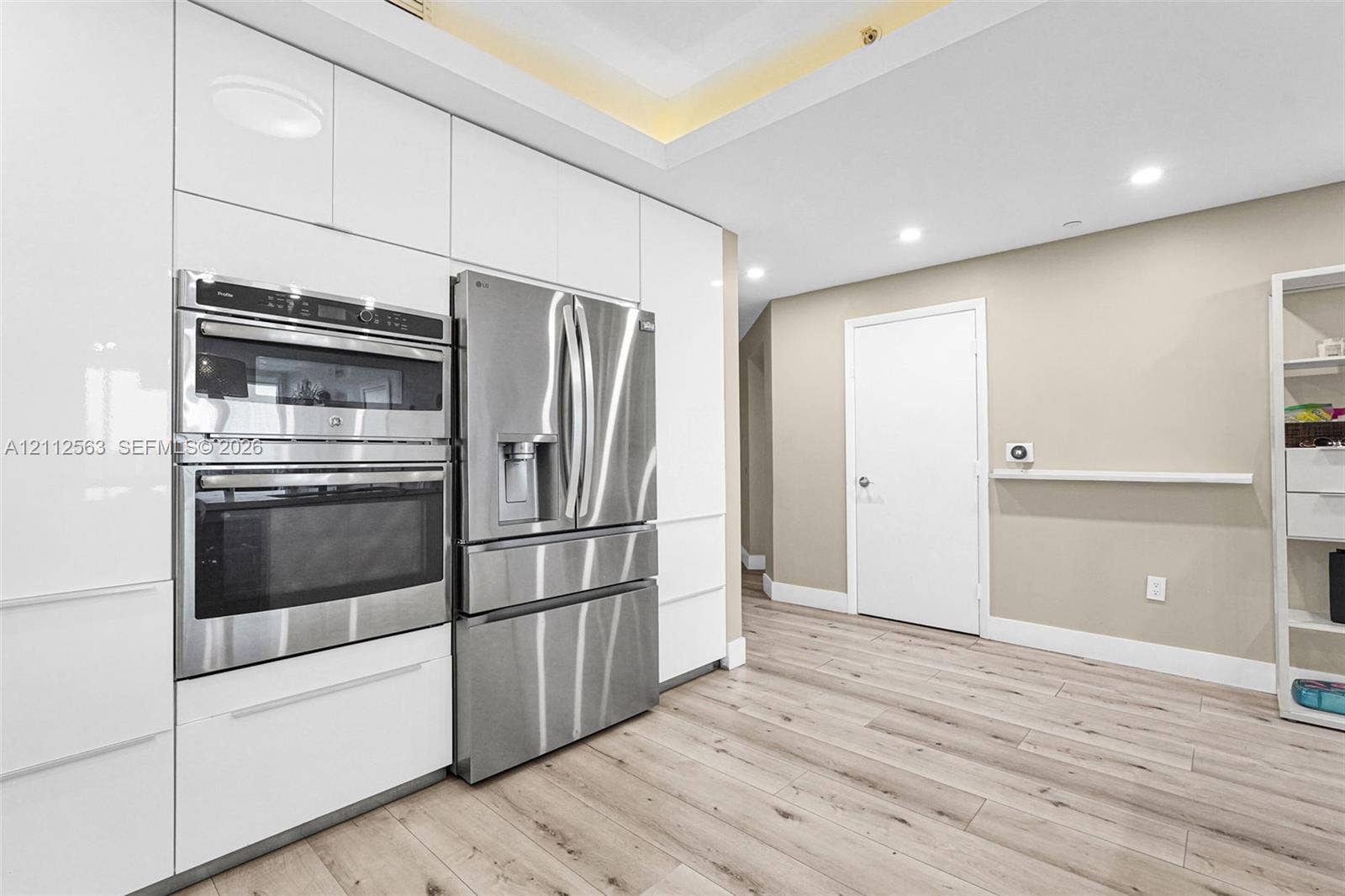 3330 NE 190th Street, #2016, Aventura, FL 33180 High-gloss white cabinetry, integrated stainless steel double wall ovens, French door stainless steel refrigerator, recessed lighting, and wood-finish flooring