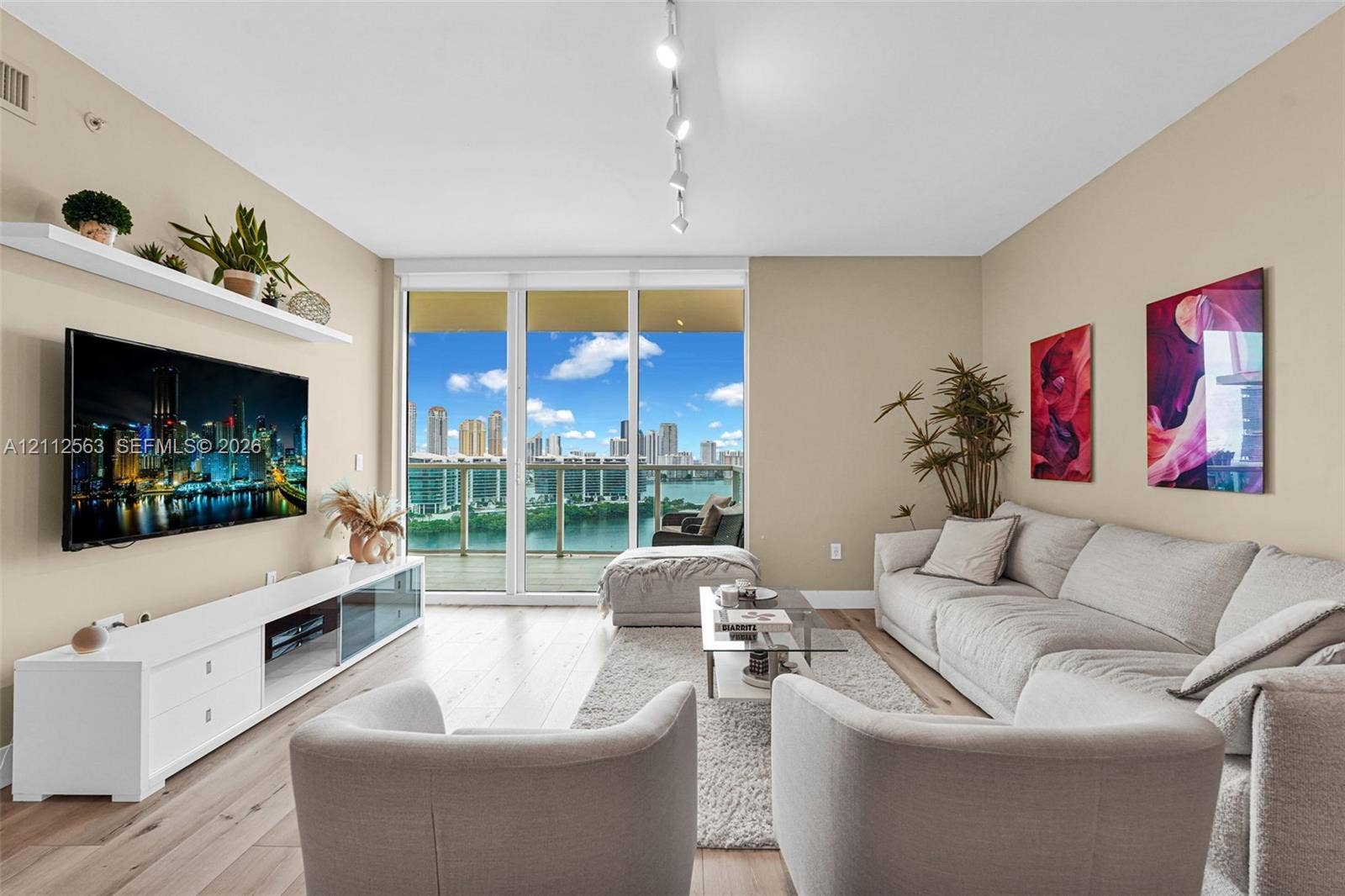 3330 NE 190th Street, #2016, Aventura, FL 33180 Living area featuring wood-finish flooring, floor-to-ceiling windows, a glass-panel balcony door, and a wall-mounted floating shelf