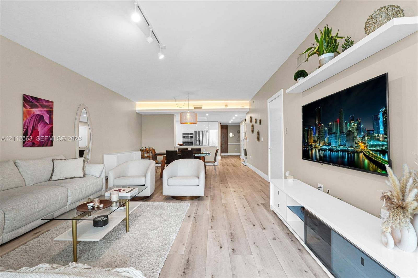 3330 NE 190th Street, #2016, Aventura, FL 33180 Open-concept room featuring wood-finish flooring, recessed track lighting, built-in wall-mounted shelving, and cove lighting