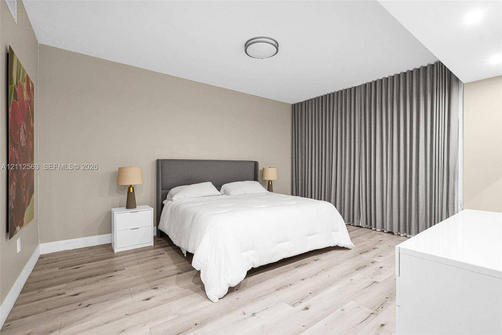 3330 NE 190th Street, #2016, Aventura, FL 33180 Neutral-toned interior featuring wood-finish flooring, floor-to-ceiling pleated drapery, and flush-mount ceiling lighting