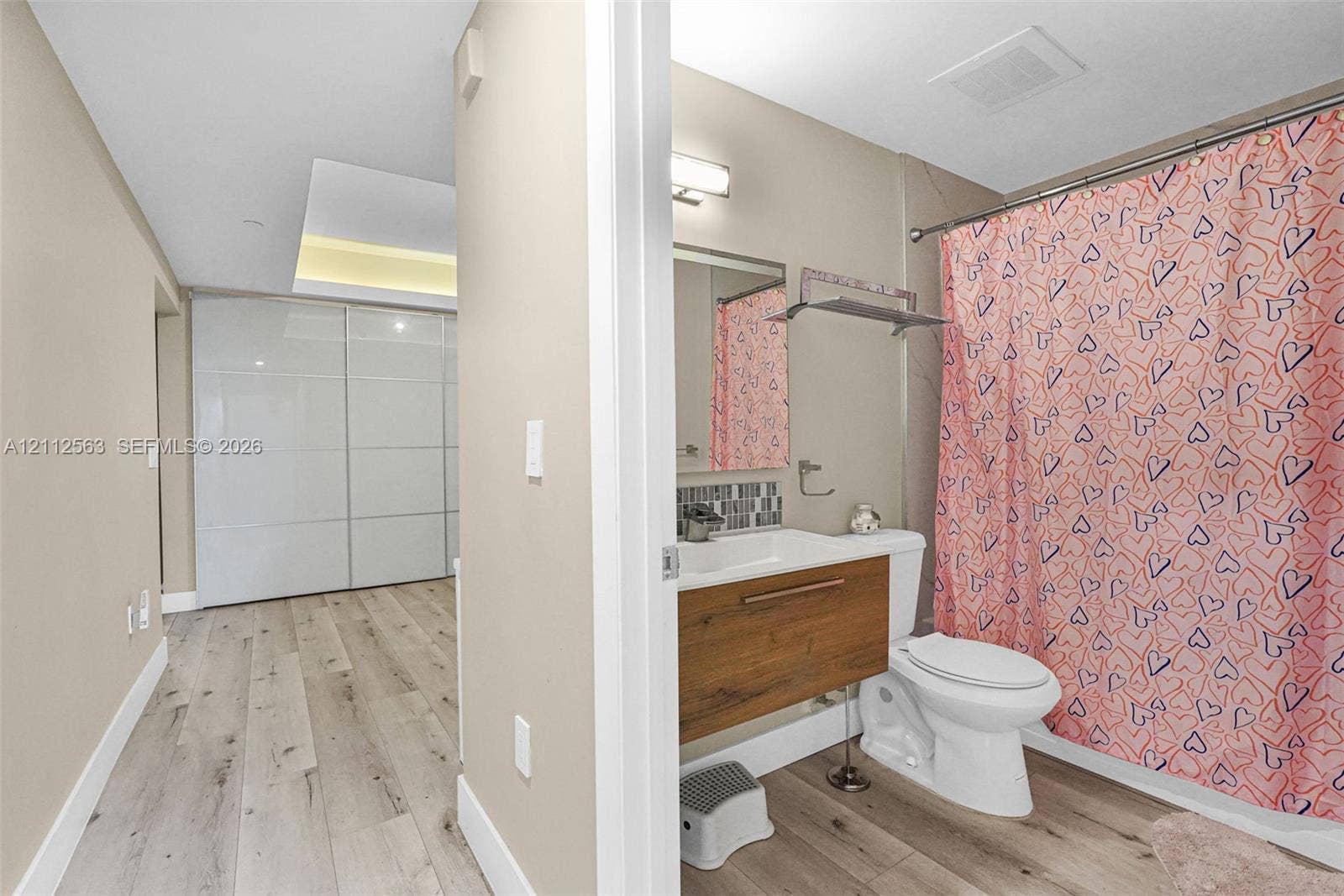 3330 NE 190th Street, #2016, Aventura, FL 33180 Bathroom featuring a wood-finish floating vanity, integrated sink, tiled backsplash, and recessed lighting, with wood-finish flooring extending into the area