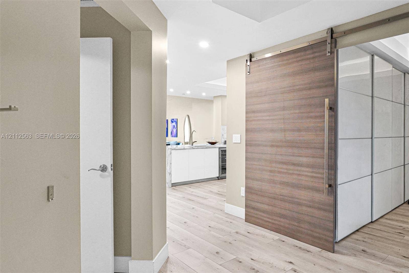 3330 NE 190th Street, #2016, Aventura, FL 33180 Wood-finish sliding barn door featuring a stainless steel track system and handle, wide-plank wood-finish flooring, and recessed ceiling lighting