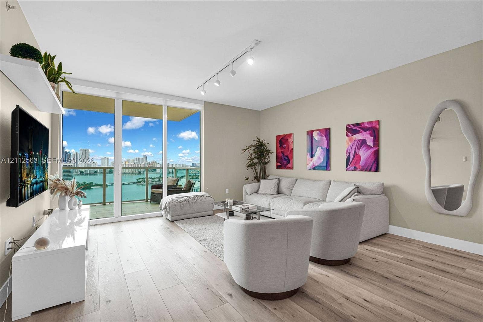 3330 NE 190th Street, #2016, Aventura, FL 33180 Floor-to-ceiling glass sliding doors, wood-finish flooring, recessed track lighting, and a private balcony featuring a water backdrop