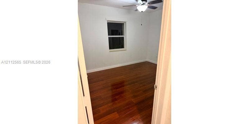 Room interior featuring polished wood-finish flooring, a ceiling fan with integrated lighting, and a single-hung window with white casing