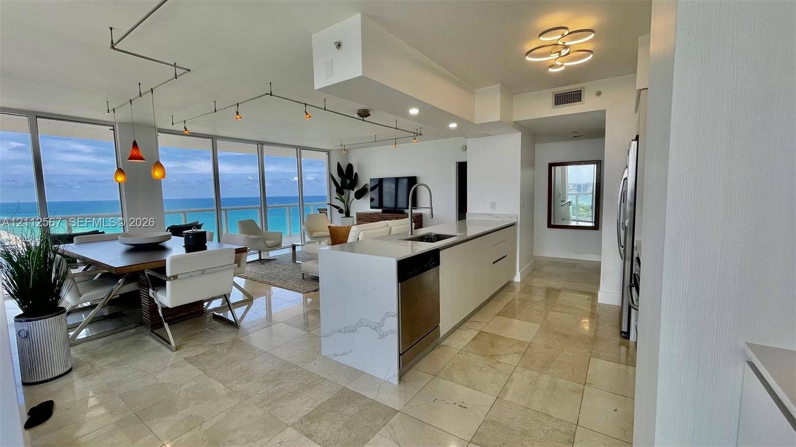 6365 Collins Avenue, #3208, Miami Beach, Miami Beach, FL 33141 Open-concept kitchen featuring an island with a stone-finish countertop, stainless steel appliances, floor-to-ceiling windows, and natural stone flooring throughout