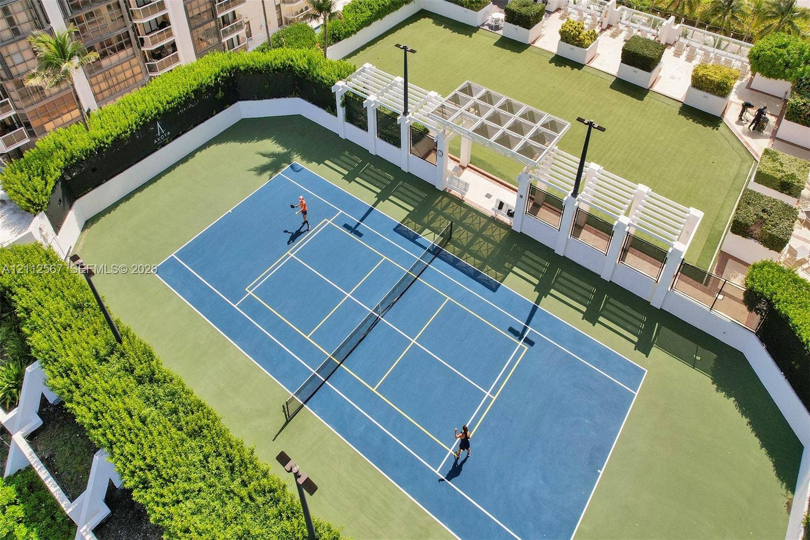 6365 Collins Avenue, #3208, Miami Beach, Miami Beach, FL 33141 Tennis court featuring a hard surface, surrounding privacy hedges, integrated lighting, and a white architectural pergola