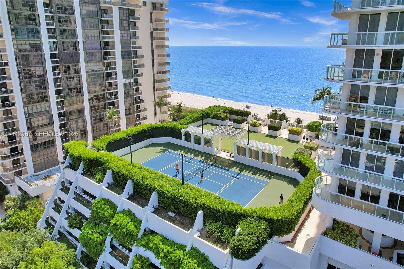 6365 Collins Avenue, #3208, Miami Beach, Miami Beach, FL 33141 Hard-surface tennis court with perimeter landscaping, pergola-covered seating area, and synthetic turf lawn