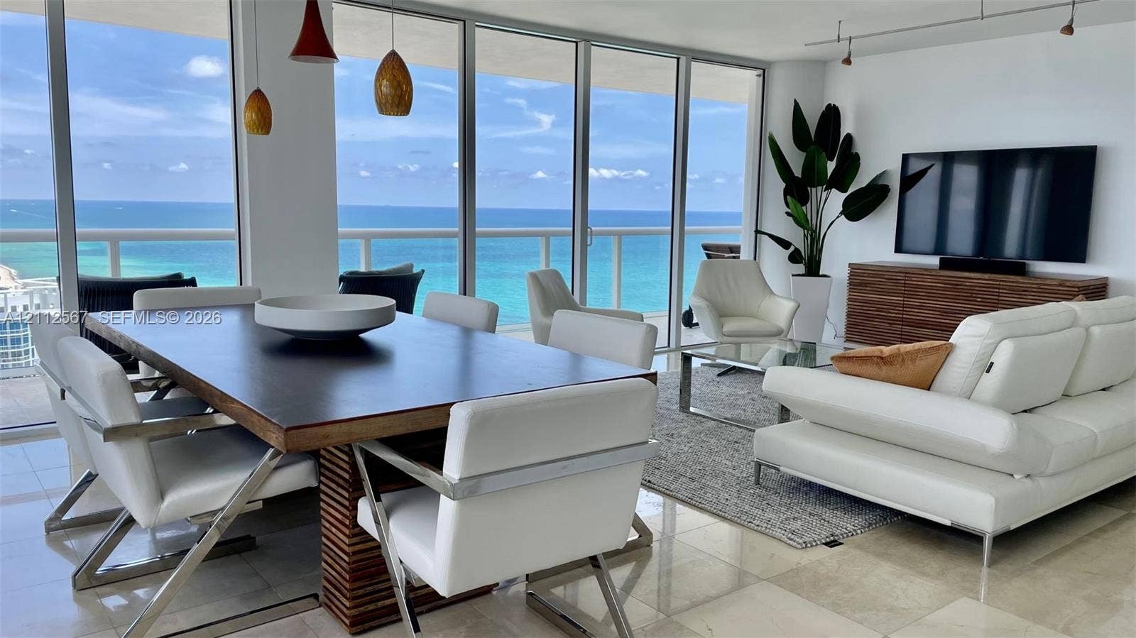 6365 Collins Avenue, #3208, Miami Beach, Miami Beach, FL 33141 Open-concept living space featuring floor-to-ceiling glass walls, polished stone flooring, recessed track lighting, and a glass-railed balcony overlooking the ocean