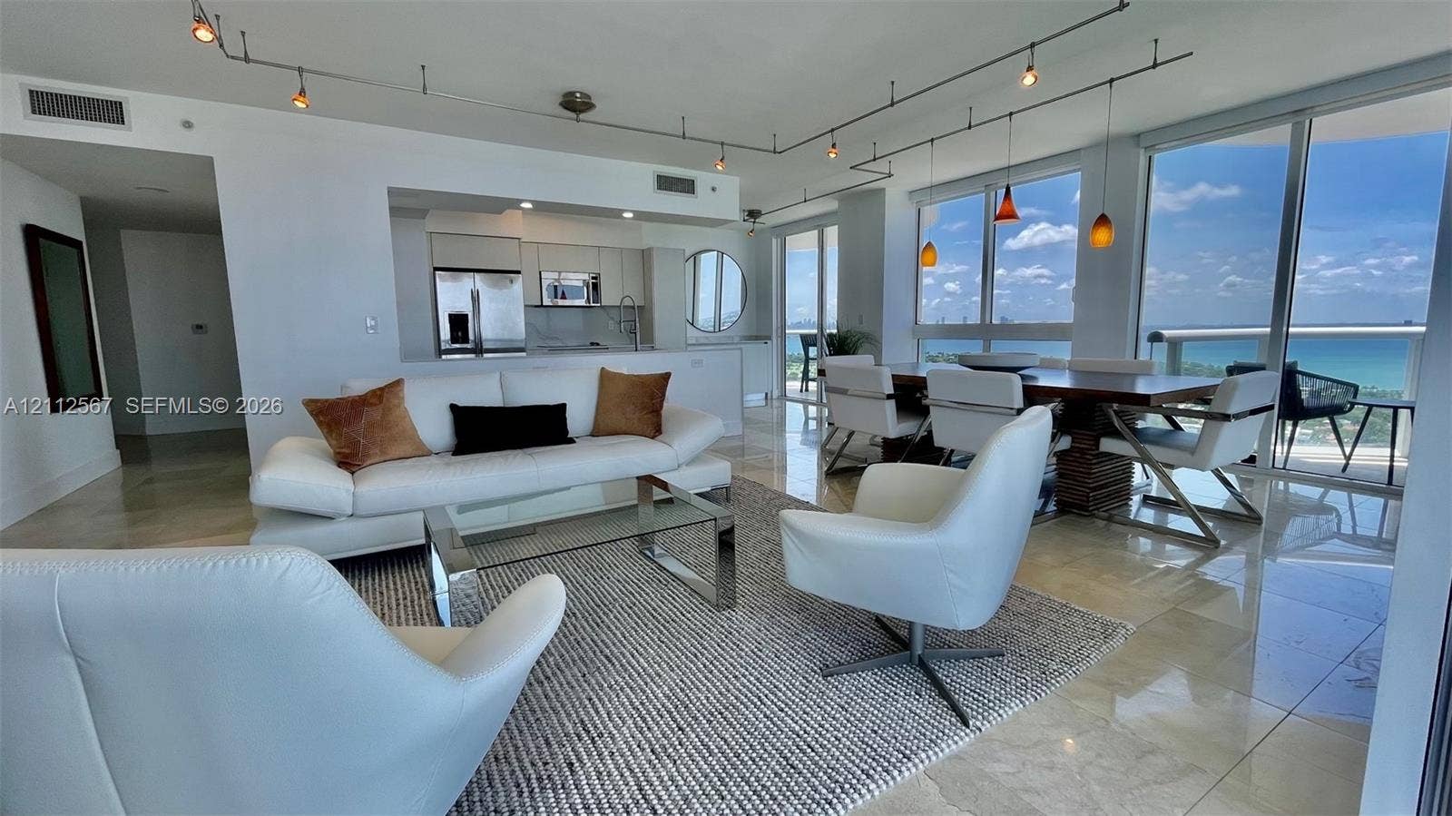 6365 Collins Avenue, #3208, Miami Beach, Miami Beach, FL 33141 Open-concept living space featuring floor-to-ceiling windows, polished stone flooring, custom track lighting, and built-in kitchen cabinetry