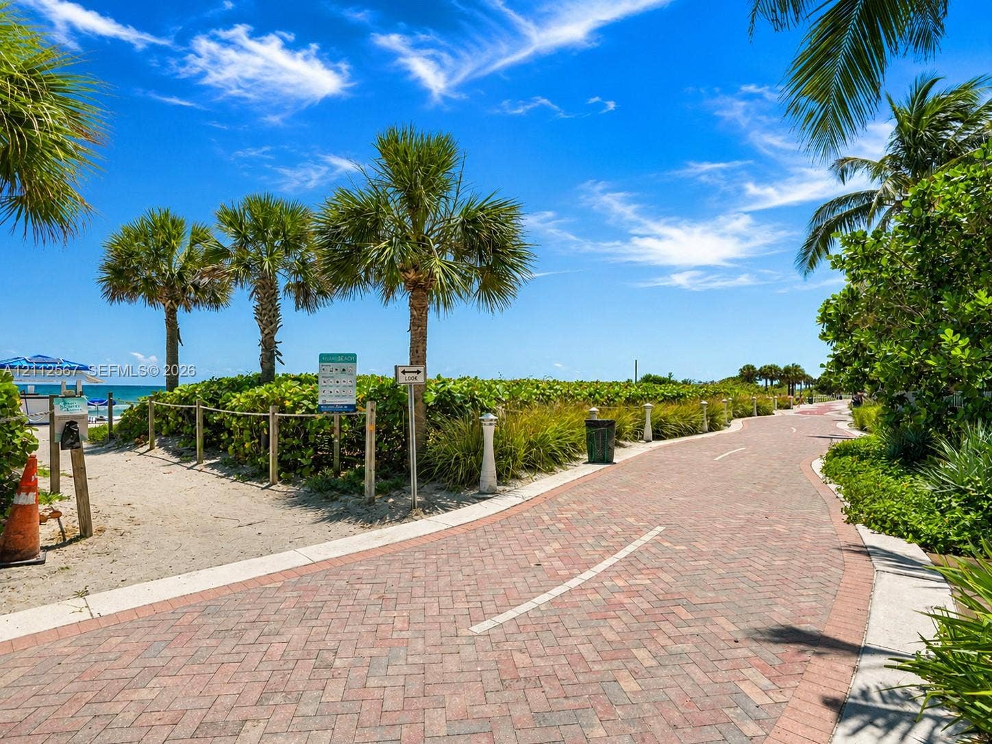 6365 Collins Avenue, #3208, Miami Beach, Miami Beach, FL 33141 Brick-paver pathway surrounded by palm trees, coastal landscaping, and access to a sandy beach