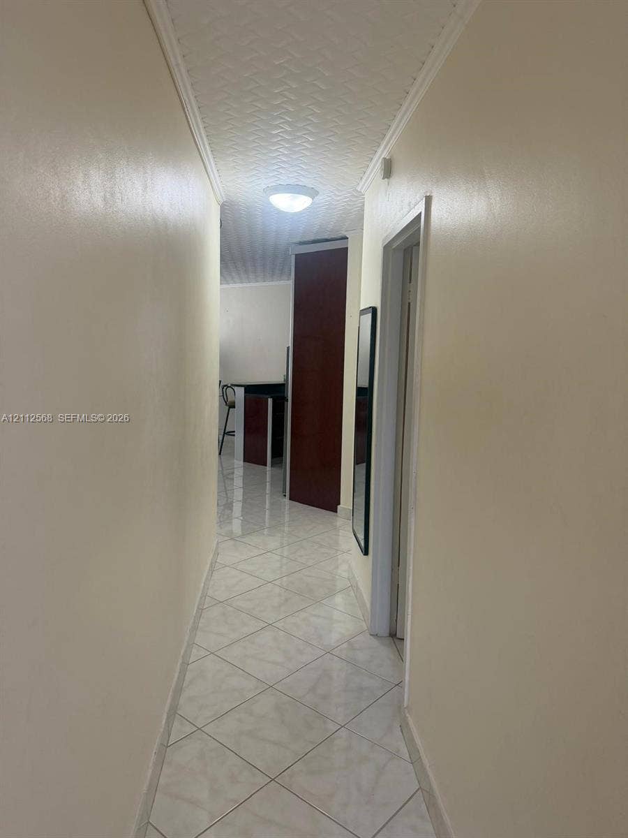 1936 S Ocean Drive, #8B, Hallandale Beach, Hallandale Beach, FL 33009 Hallway featuring neutral wall tones, large-format diamond-pattern floor tiles, and a textured ceiling finish with a flush-mount light fixture