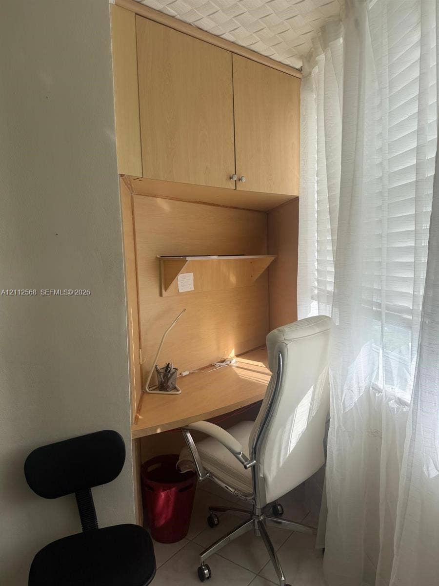 1936 S Ocean Drive, #8B, Hallandale Beach, Hallandale Beach, FL 33009 Built-in wood-finish cabinetry featuring an integrated desk surface, overhead storage, and a fixed wall-mounted shelf