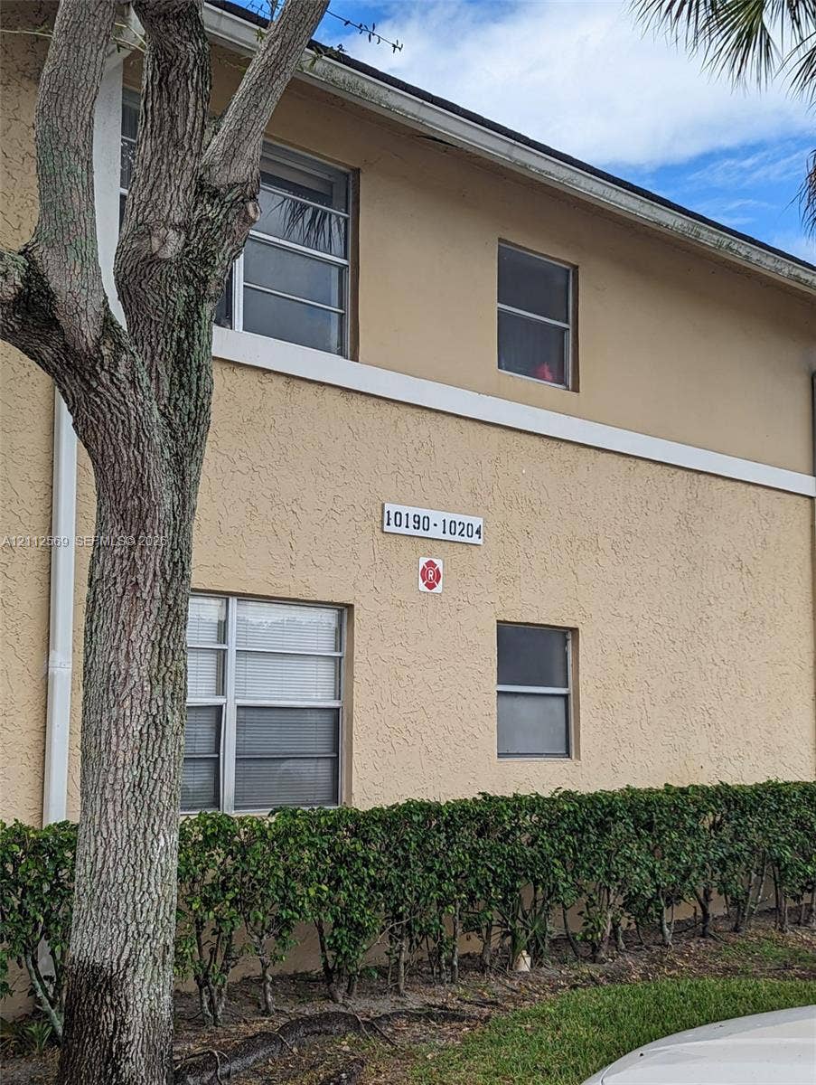 Stucco exterior featuring a two-story profile, horizontal trim accents, and installed window screens