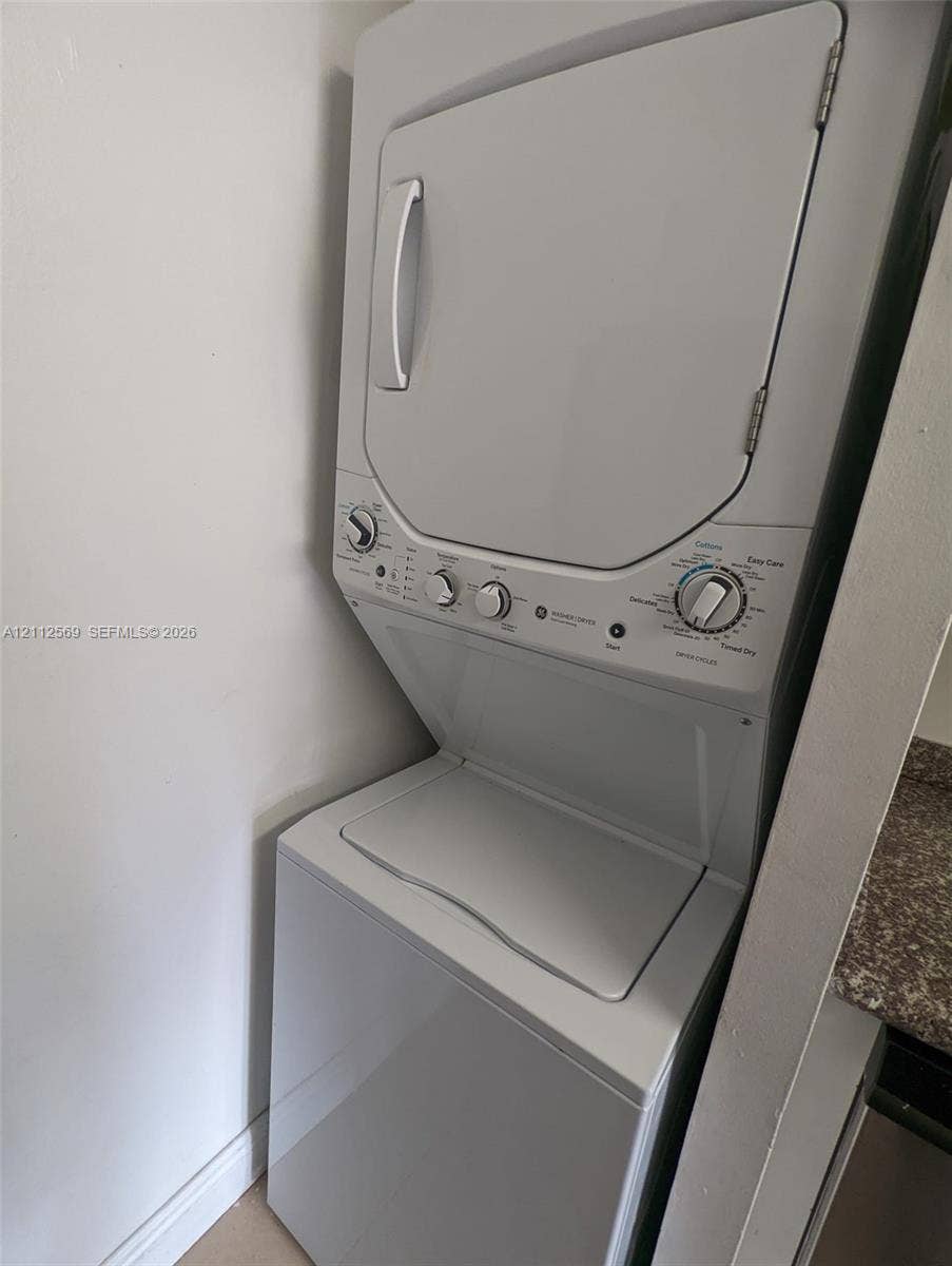 Stacked white laundry center featuring a top-loading washer and integrated dryer
