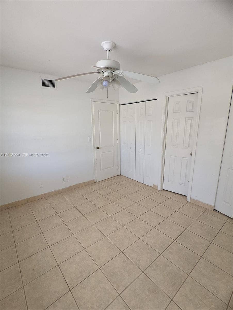 Ceramic tile flooring, white six-panel interior doors, and a ceiling fan with integrated lighting