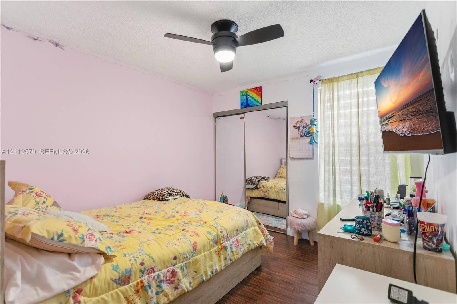 Bedroom featuring wood-finish flooring, a ceiling fan with integrated lighting, and a closet with sliding mirrored doors