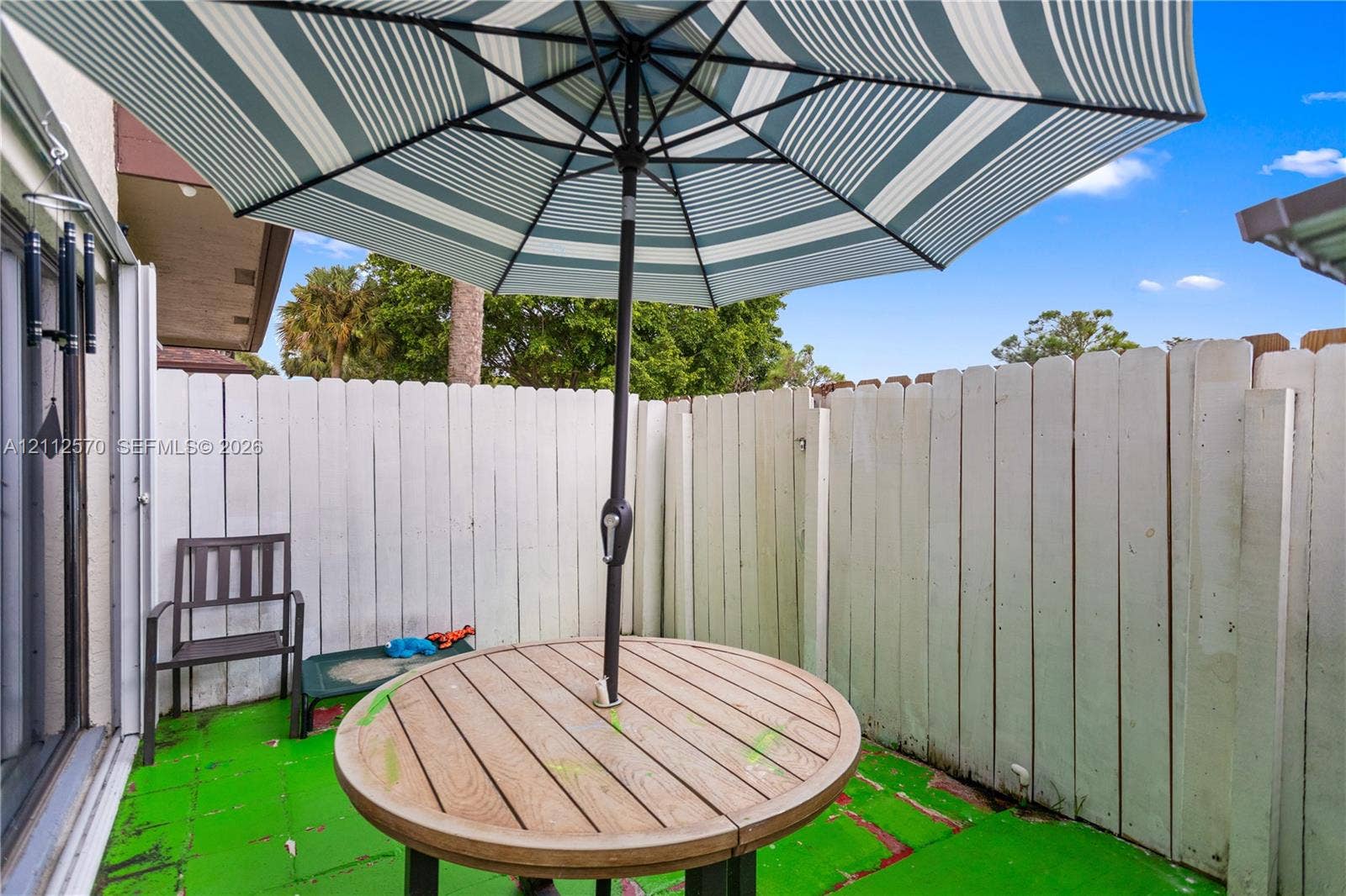 Enclosed patio featuring vertical wood-slat privacy fencing and paved ground surface