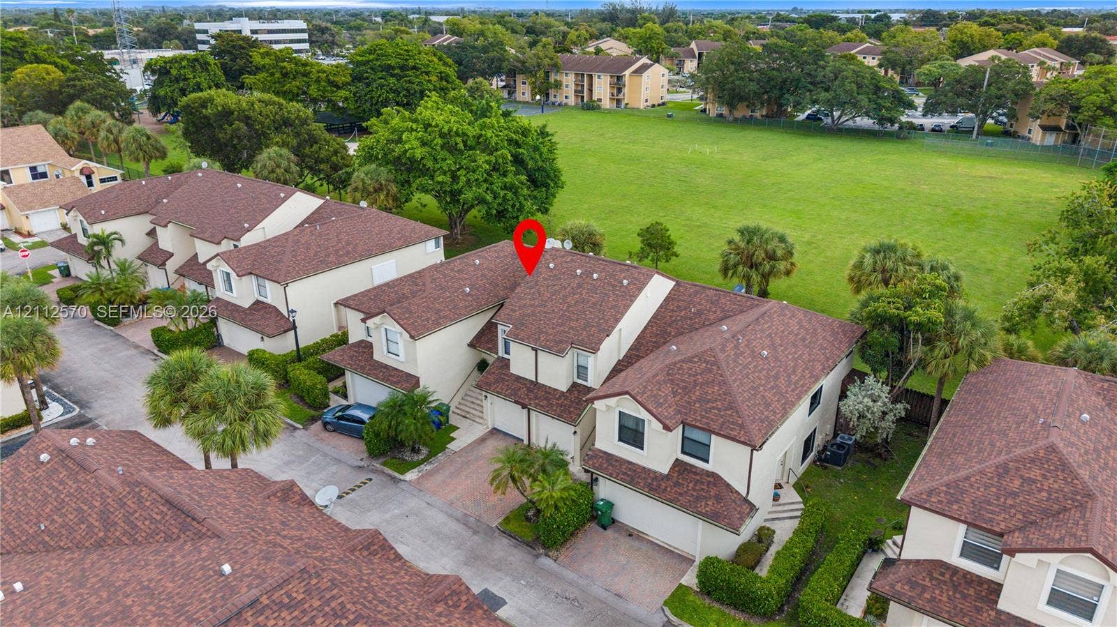 Aerial perspective of a multi-story residence featuring a shingled roof, stucco exterior, paved driveway, and attached garage