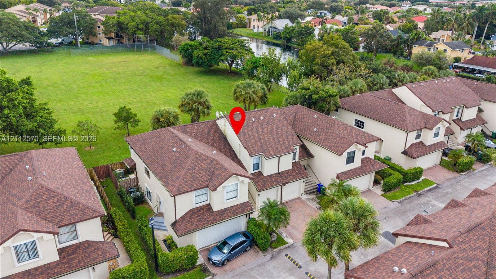 Multi-level exterior featuring a shingled roof, stucco siding, paved driveway, attached garage, and mature palm landscaping