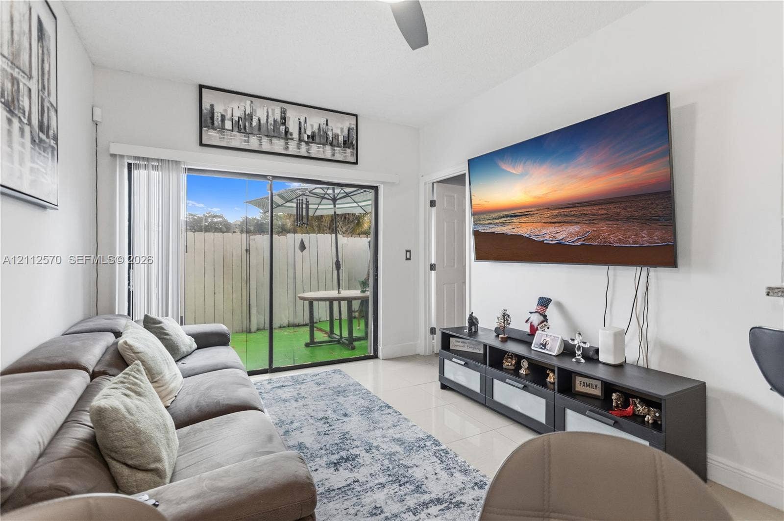 Living space featuring large format neutral tile flooring, recessed ceiling fan, and sliding glass patio doors providing natural light