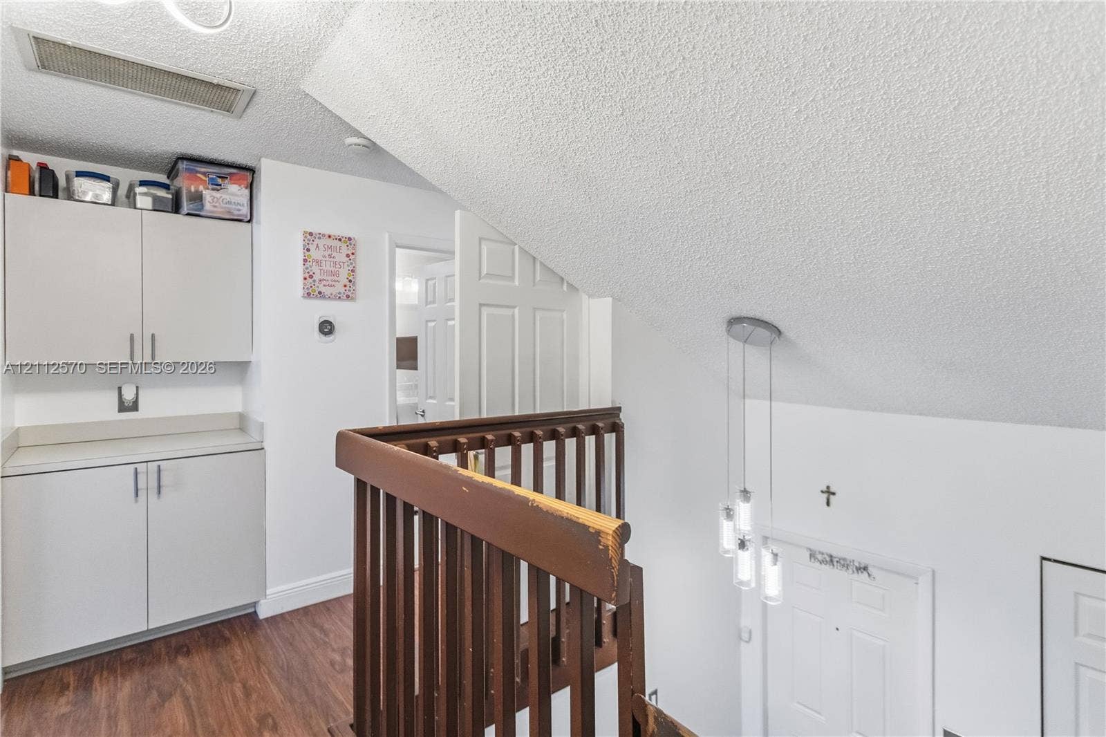 Built-in cabinetry with solid-surface countertops, wood-finish flooring, multi-light pendant fixture, and traditional wood railings