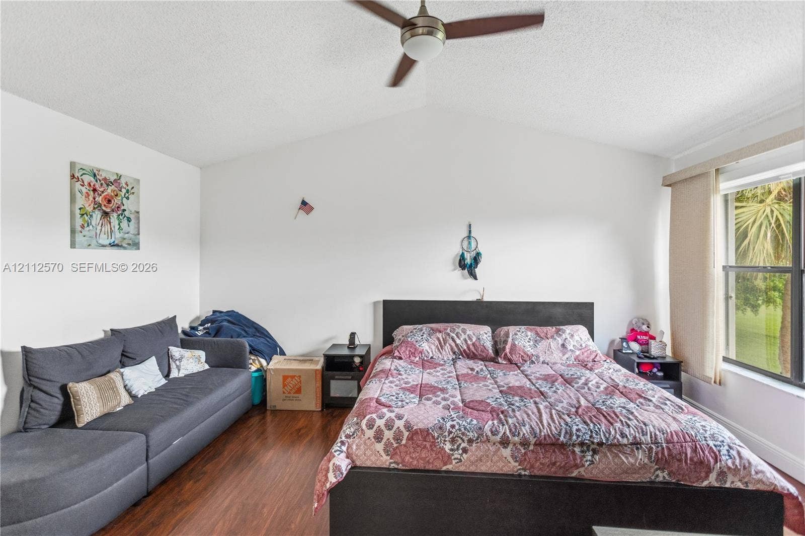 Vaulted ceiling featuring a ceiling fan with integrated lighting and dark wood-finish flooring