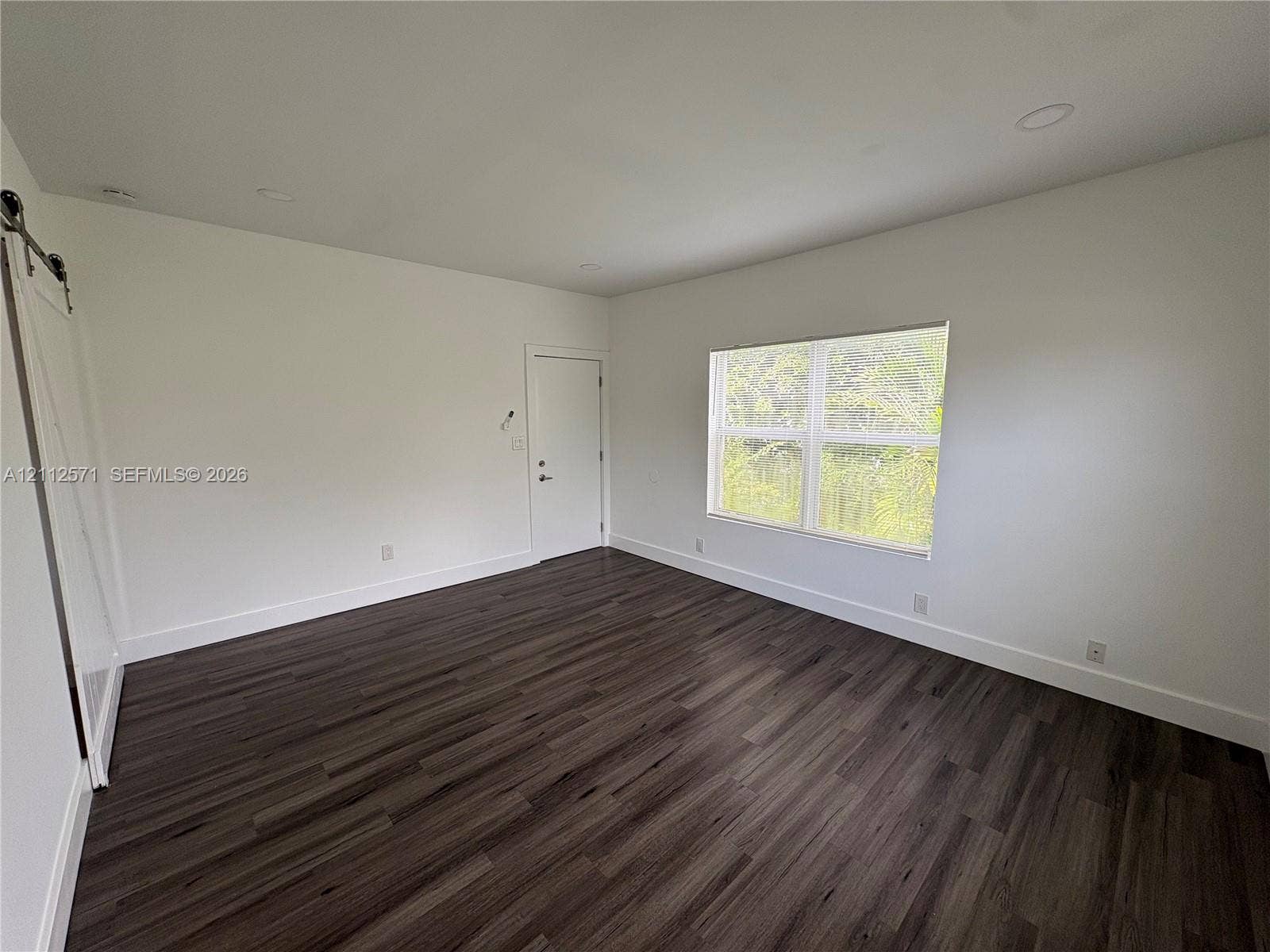 Interior space featuring wood-finish flooring, recessed lighting, and a white sliding barn door