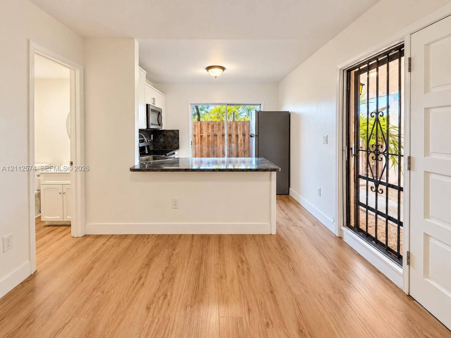 Kitchen featuring wood-finish flooring, stone-surfaced peninsula, and built-in cabinetry, including an exterior metal security door