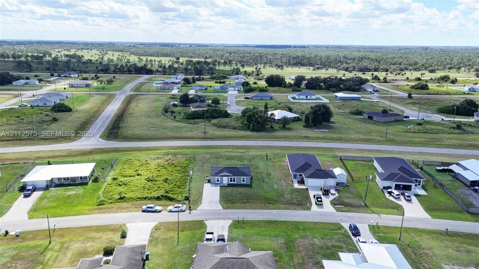 9041 E Broad, Labelle, FL 33935 Aerial perspective of a residential street featuring paved roads, concrete driveways, and expansive undeveloped acreage