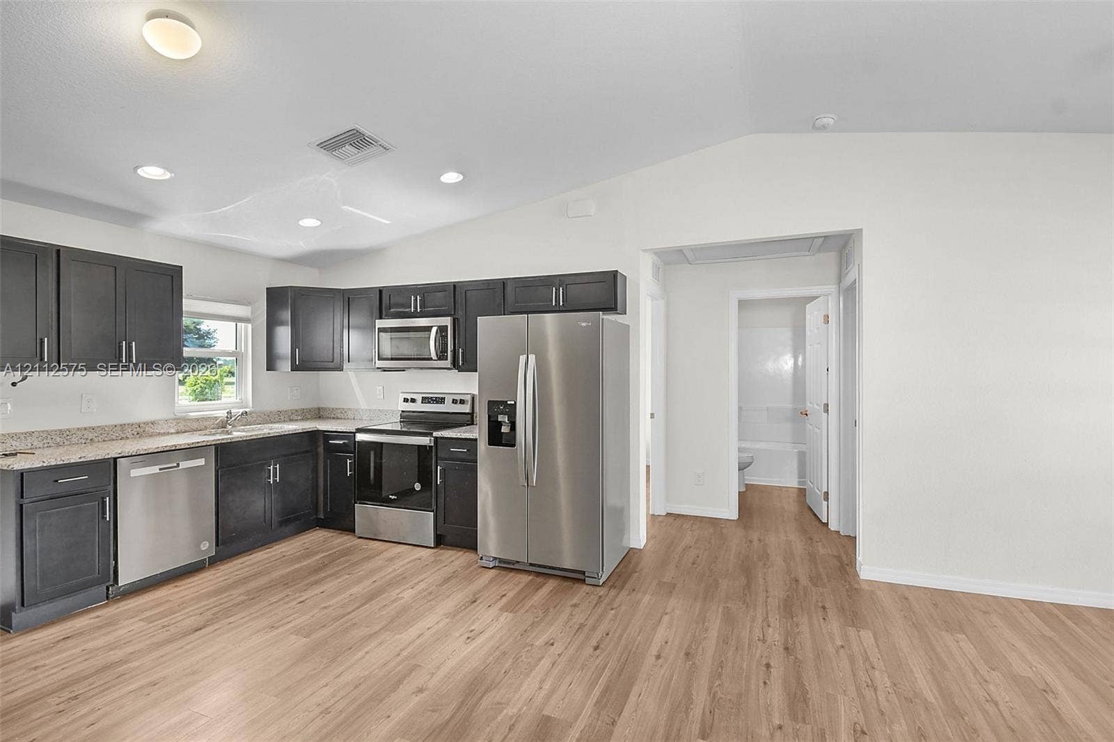 9041 E Broad, Labelle, FL 33935 Kitchen featuring charcoal-toned cabinetry, light-toned stone-finish countertops, stainless steel appliances, recessed lighting, and wood-finish flooring