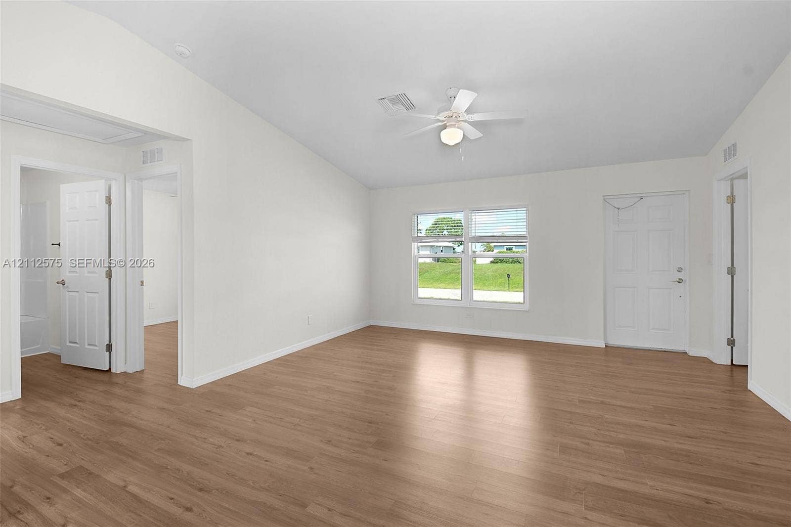 9041 E Broad, Labelle, FL 33935 Interior space featuring wood-finish flooring, vaulted ceilings, a central ceiling fan with integrated lighting, dual-pane windows, and multi-panel interior doors