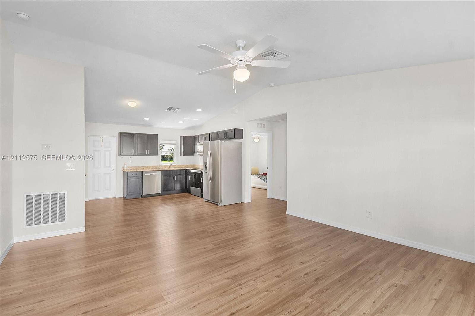 9041 E Broad, Labelle, FL 33935 Open-concept area featuring vaulted ceilings, wood-finish flooring, ceiling fan, and cabinetry with stainless steel appliances