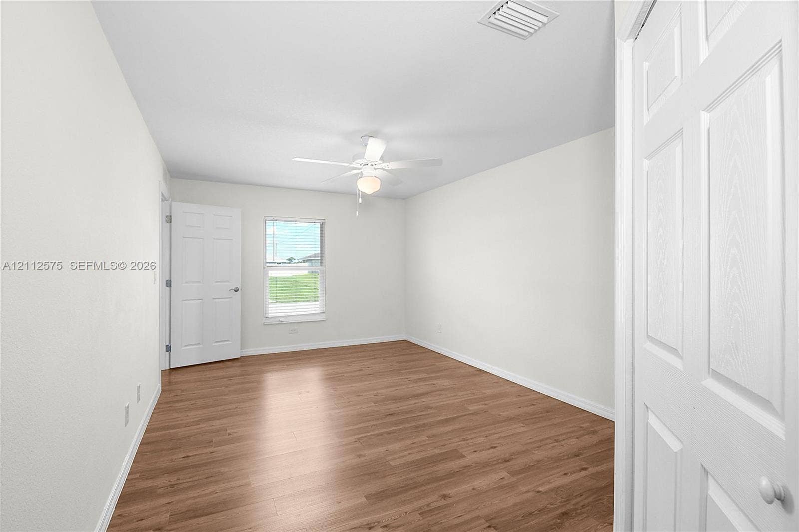 9041 E Broad, Labelle, FL 33935 Room featuring wood-finish flooring, a white ceiling fan with integrated light, a single-hung window, and white six-panel interior doors