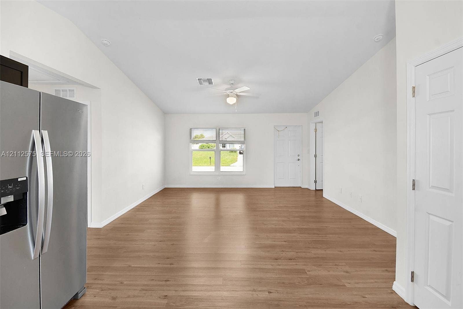 9041 E Broad, Labelle, FL 33935 Open interior space featuring wood-finish flooring, vaulted ceilings, a ceiling fan with light fixture, and large windows providing natural illumination
