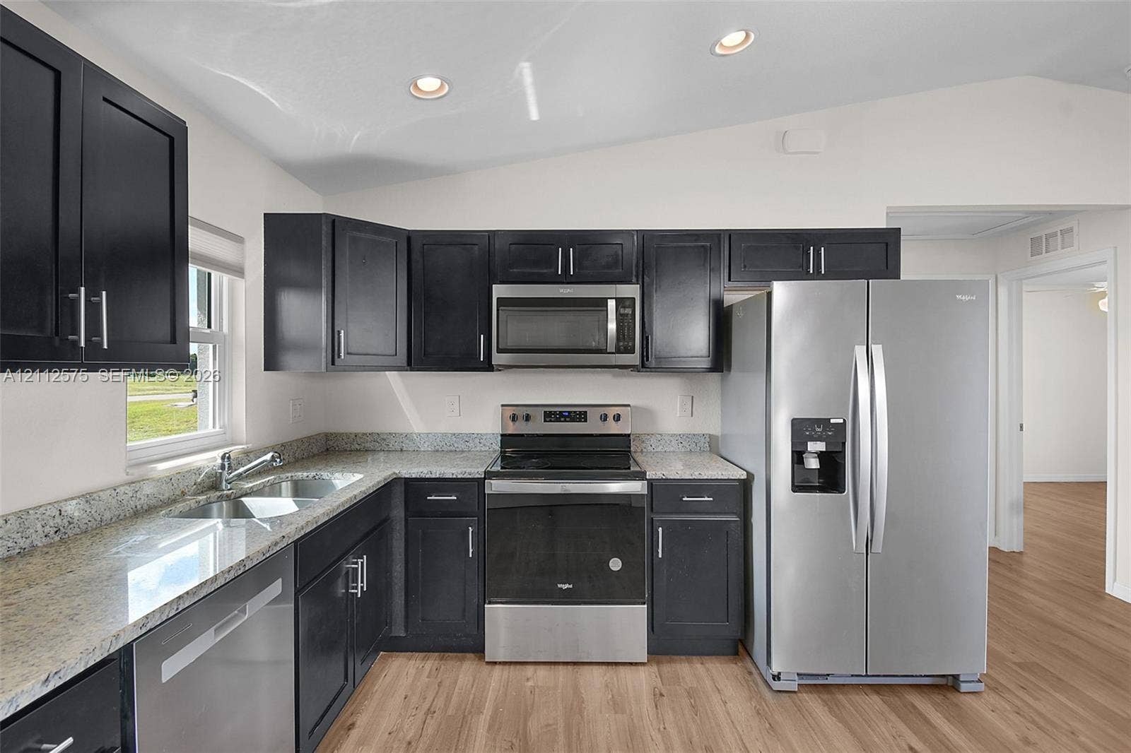 9041 E Broad, Labelle, FL 33935 Kitchen featuring dark cabinetry, stone-finish countertops, stainless steel appliances, and wood-finish flooring
