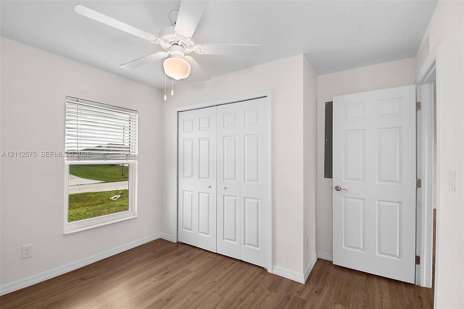 9041 E Broad, Labelle, FL 33935 Wood-finish flooring, white paneled interior doors, double-door closet, neutral wall paint, and overhead ceiling fan with integrated lighting
