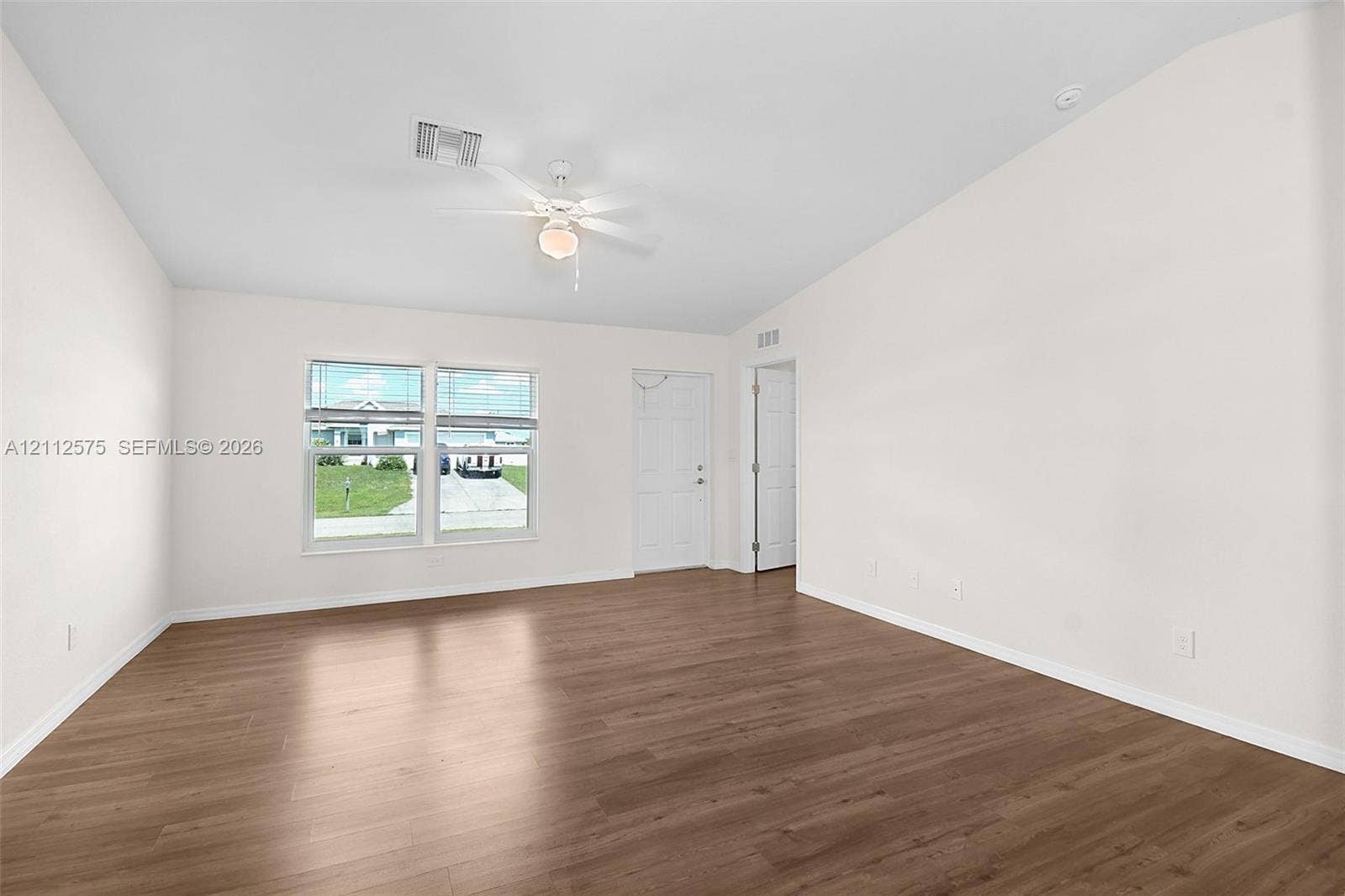 9041 E Broad, Labelle, FL 33935 Neutral-toned interior featuring wood-finish flooring, vaulted ceilings, multi-pane windows, and an attached ceiling fan with integrated lighting