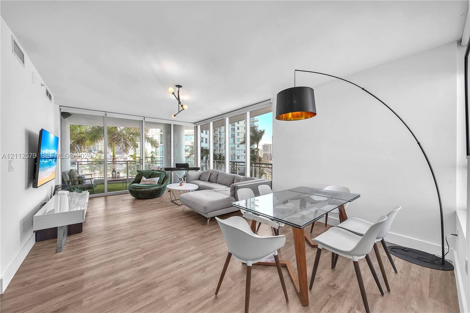 Open-concept living space featuring wood-finish flooring, floor-to-ceiling windows, a glass sliding door, and a multi-arm geometric ceiling fixture