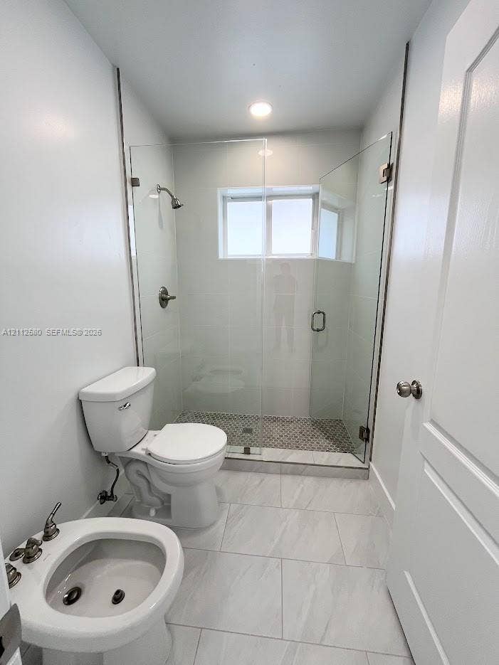 Walk-in shower featuring a frameless glass enclosure, patterned tile flooring, and metallic fixtures