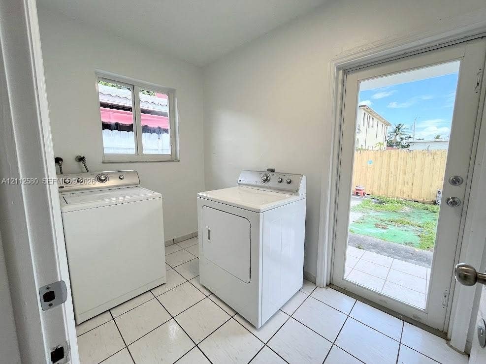 Laundry room featuring large-format ceramic tile flooring, a window, and a glass-paneled exterior door